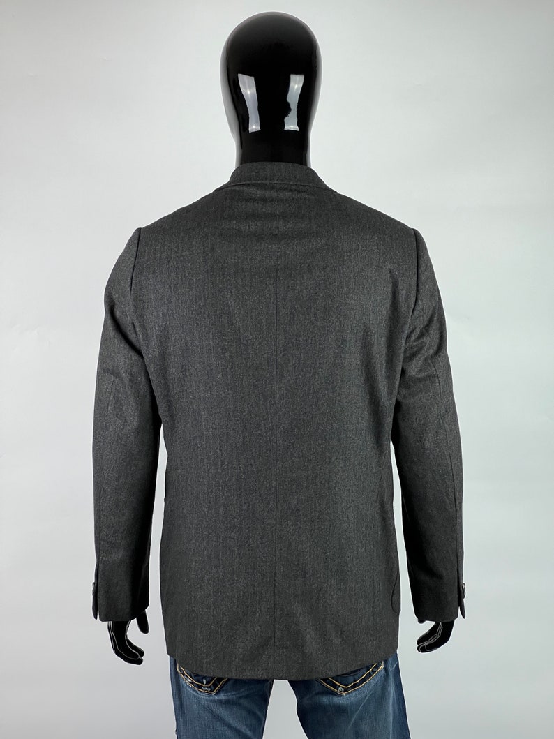 May include: A dark gray blazer with a single button closure and long sleeves. The blazer is made of a textured fabric and has a classic fit.