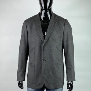 May include: A gray blazer with a two-button closure and two flap pockets. The blazer is made of a textured fabric.