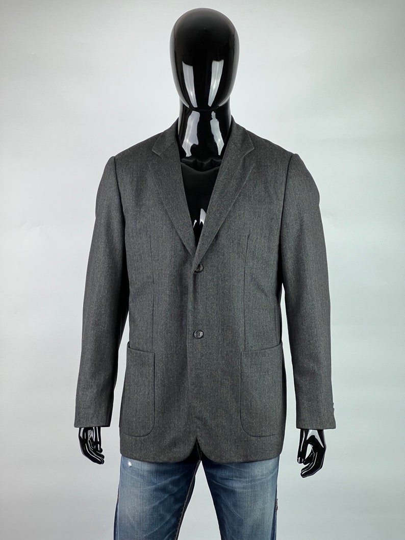 May include: A gray blazer with a two-button closure and two flap pockets. The blazer is made of a textured fabric.