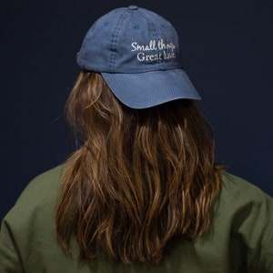 May include: A blue baseball cap with the text "Small things, Great love" embroidered on the front.