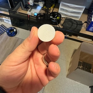 May include: A white, round, textured disc.