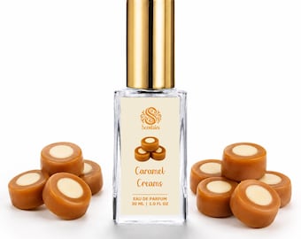 May include: A rectangular glass perfume bottle with a gold cap, featuring a label with the text Scentsies, Caramel Creams, and 30 ml | 1.0 fl oz. The bottle is surrounded by several round, brown caramel sweets with white centres.