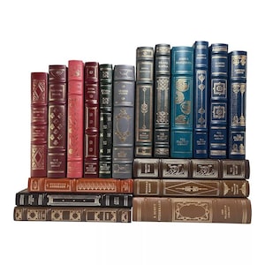 May include: A collection of antique books with leather-bound covers in various colors, including burgundy, pink, green, and blue. The books are arranged in two rows, with gold lettering and decorative details on the spines. The books are from The Franklin Library.