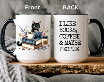 May include: White ceramic mug with a black handle and rim. The front of the mug features a black cat sitting on a stack of books with a cup of coffee. The back of the mug has the text "I like books, coffee & maybe people".