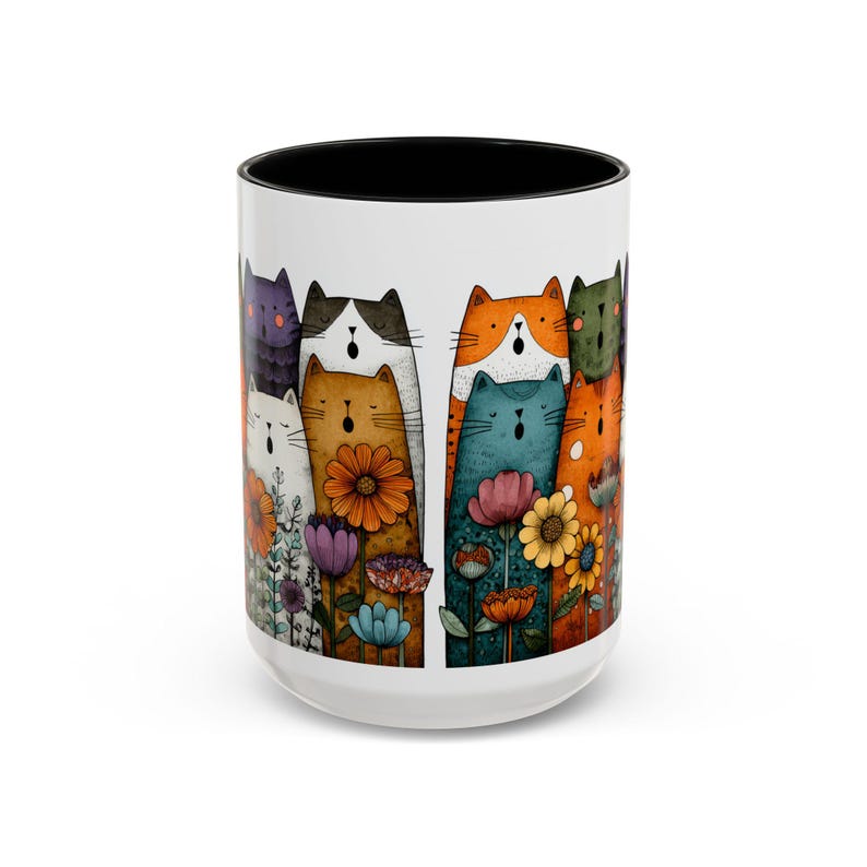 May include: White ceramic mug with a black interior featuring a colorful illustration of stylized cats and flowers. The cats are various colors, including orange, blue, and purple, and are interspersed with vibrant flowers.