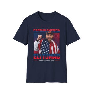 Peut inclure: T-shirt bleu marine avec un graphisme d'un homme envelopp&eacute; dans un drapeau am&eacute;ricain, avec le texte "CAPTAIN AMERICA" au-dessus et "ELI TOMAC" en dessous. Le t-shirt comprend &eacute;galement "RED BULL KTM FACTORY RACING".