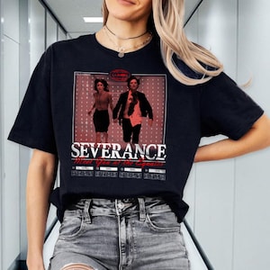 May include: Black t-shirt with a graphic of two people running in a hallway. The graphic is in a red and white color scheme and includes the text "Severance Meet You at the Equator".