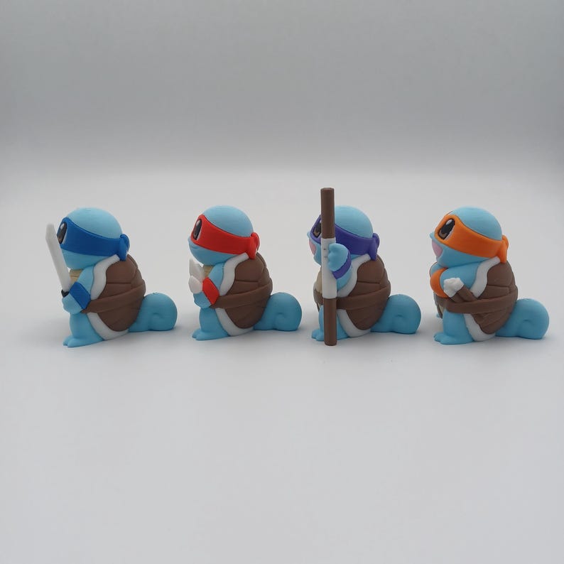 May include: Four blue turtle figurines with different coloured bandanas and weapons. The turtles are in a line, facing the right side of the image.
