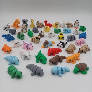 May include: A collection of 30 colorful animal figurines made of polymer clay. The figurines include a variety of animals, such as a turtle, a penguin, a koala, a platypus, a ladybug, a bee, a snail, a caterpillar, a frog, a lizard, a snake, a fish, a bird, a butterfly, a spider, a scorpion, a crab, a lobster, a shrimp, a starfish, a seahorse, a dolphin, a whale, a shark, a jellyfish, a sea urchin, a sea anemone, and a coral.