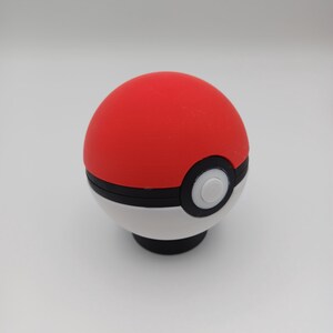 May include: A red and white Pok&eacute; Ball with a black stripe and a white button. The top half is red, the bottom half is white, and the button is white with a black outline. The ball is a sphere.