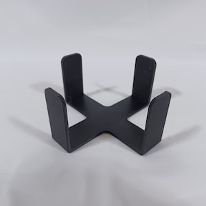 May include: A black plastic stand with four upright sections forming a square shape. The stand is designed to hold items in place.