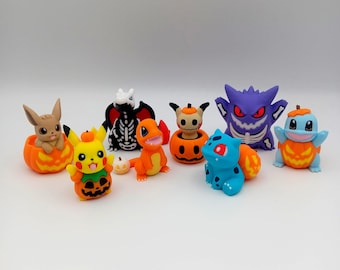 May include: A collection of colorful figurines featuring popular characters, each with a Halloween theme. The figurines include Pikachu, Charmander, and others, all with pumpkin-themed designs. The figures are set against a plain white background.