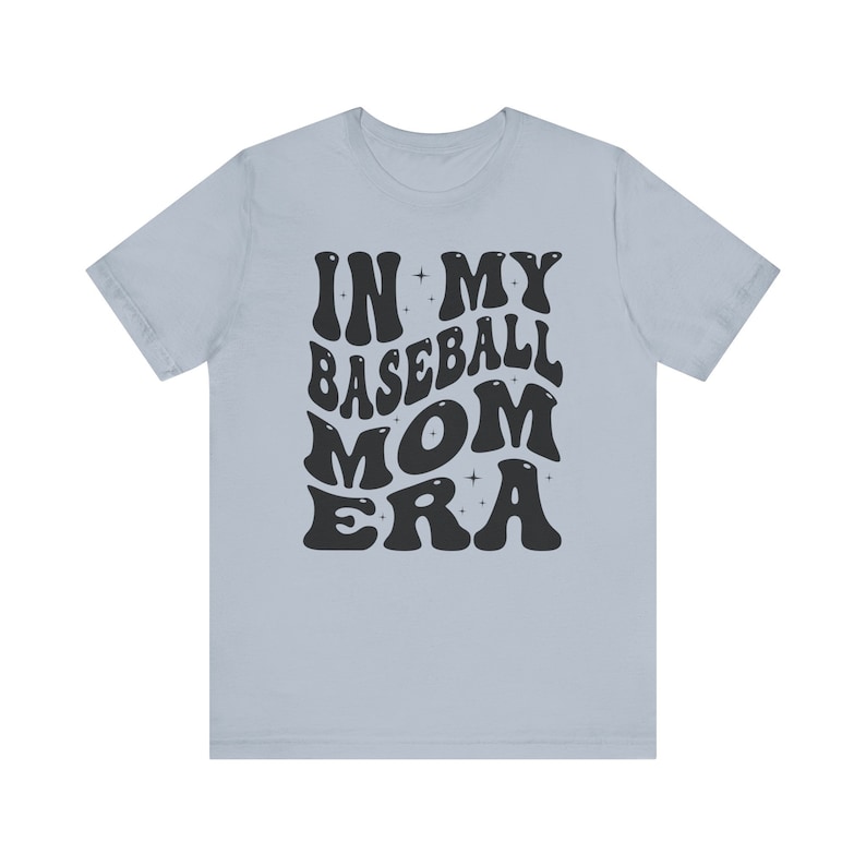 May include: Light blue t-shirt with black text that reads "In My Baseball Mom Era" in a retro font.