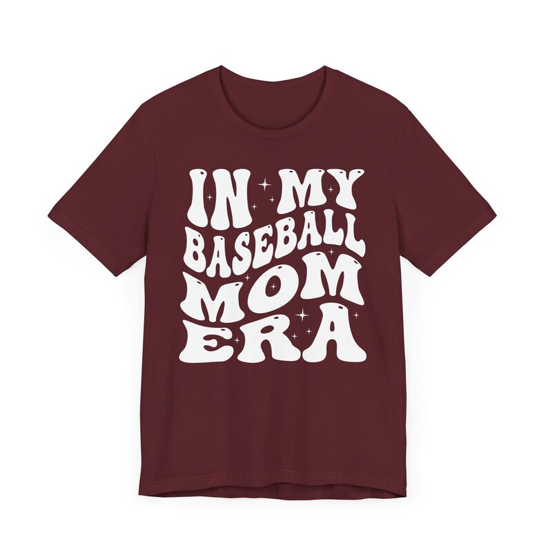 May include: Burgundy t-shirt with white text that reads "In My Baseball Mom Era" in a retro font.