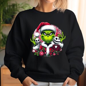 May include: Black sweatshirt featuring a colorful graphic of the Grinch wearing a Santa hat, with Jack Skellington and a skeleton. The Grinch is green, and the design includes red, white, and black accents, perfect for the holiday season.