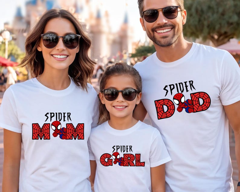 May include: Three people wearing white t-shirts with Spider-Man themed designs. The shirts read "Spider Mom", "Spider Dad", and "Spider Girl" in red and black lettering, with a Spider-Man graphic. All are wearing sunglasses.