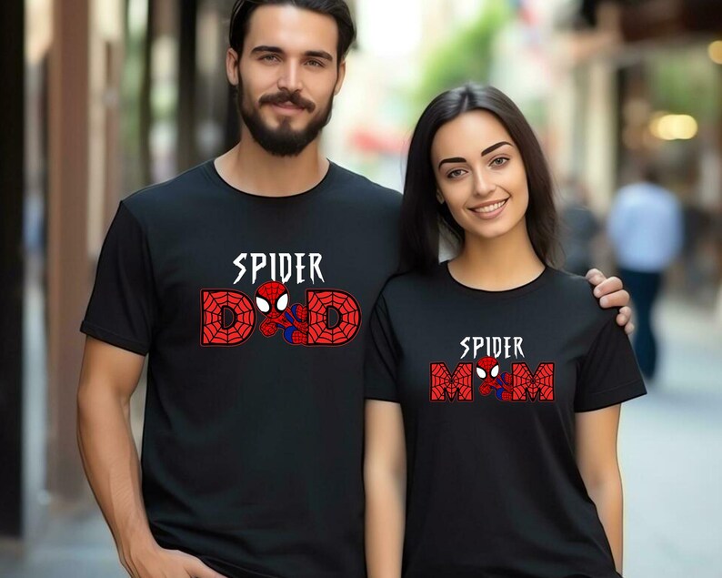 May include: Black t-shirts with Spider-Man designs. One shirt says "SPIDER DAD" with a Spider-Man graphic, and the other says "SPIDER MOM" with a Spider-Man graphic. The text is in white and red.
