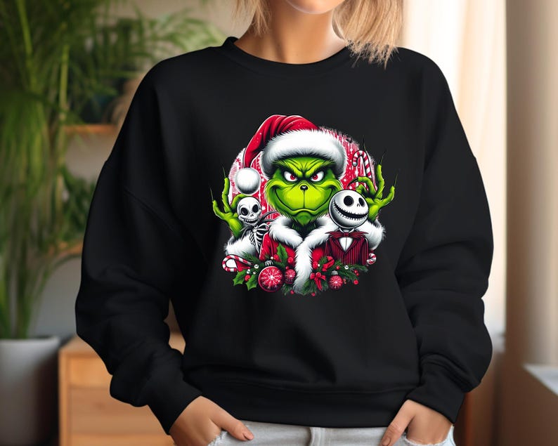May include: Black sweatshirt featuring a colorful graphic of the Grinch wearing a Santa hat, with Jack Skellington and a skeleton. The Grinch is green, and the design includes red, white, and black accents, perfect for the holiday season.