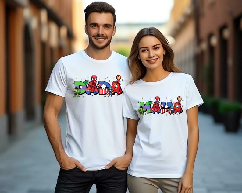 May include: White t-shirts with colorful text and superhero graphics. One shirt says "DAD" with Hulk, Spider-Man, Captain America, and Iron Man. The other shirt says "MAMA" with the same characters.