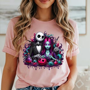 Pode incluir: Camiseta rosa claro com um gr&aacute;fico colorido de Jack Skellington e Sally de The Nightmare Before Christmas. O design inclui frascos de po&ccedil;&otilde;es, uma ab&oacute;bora e detalhes roxos gotejantes, ideal para o Halloween.