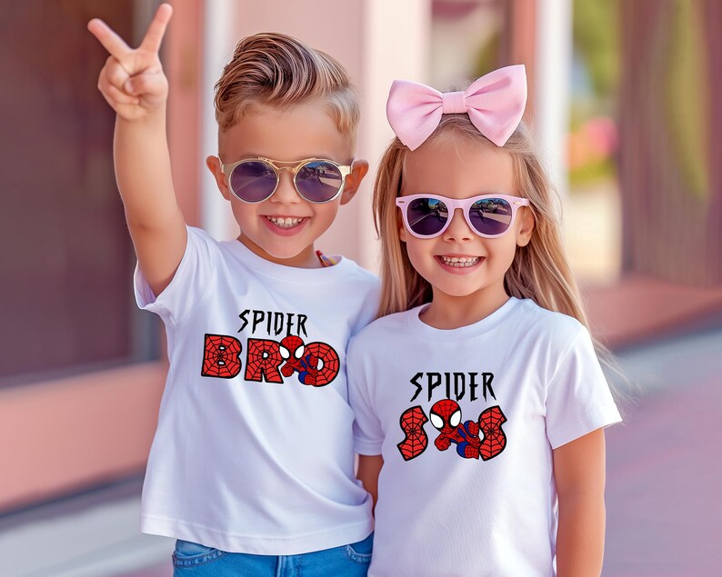 May include: Two children wearing white t-shirts with a Spider-Man graphic. One shirt says "Spider Bro" and the other says "Spider Sis". Both children are wearing sunglasses and smiling. One child is holding up two fingers.
