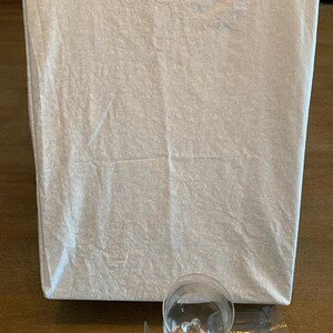 May include: Three clear glass drinking glasses, two with stems and one without, on a wooden surface. The glasses are stacked on top of each other.