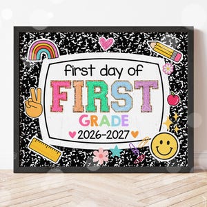 May include: A rectangular sign with a black and white composition notebook pattern background. The center features the text first day of FIRST GRADE 2026-2027 surrounded by colorful icons including a rainbow, pencil, apple, ruler, and smiley face.