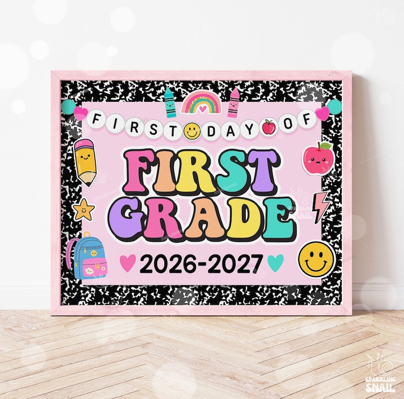 May include: A rectangular sign with a pink background and black and white composition notebook border. It features the text FIRST DAY OF FIRST GRADE 2026-2027, decorated with colorful illustrations of a rainbow, pencil, apple, and backpack.