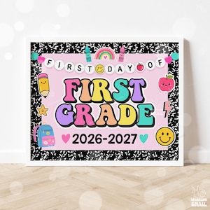 May include: A rectangular sign with a black and white composition notebook pattern border. The center is light pink with the text FIRST DAY OF FIRST GRADE 2026-2027. It features colorful illustrations of a rainbow, pencil, apple, backpack, and smiley faces.