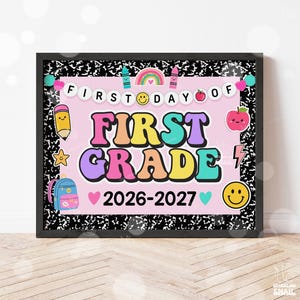 May include: A framed sign with a black and white composition notebook pattern border. The center is light pink with the text FIRST DAY OF FIRST GRADE 2026-2027. It features colorful illustrations of a rainbow, pencil, apple, backpack, and smiley faces.
