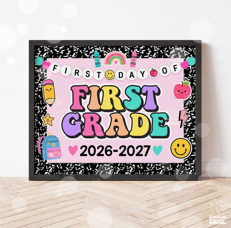 May include: A framed sign with a black and white composition notebook pattern border. The center is light pink with the text FIRST DAY OF FIRST GRADE 2026-2027. It features colorful illustrations of a rainbow, pencil, apple, backpack, and smiley faces.