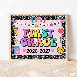 May include: A rectangular sign with a black and white composition notebook pattern border surrounding a light pink center. The text reads FIRST DAY OF FIRST GRADE 2026-2027. Graphics include a rainbow, smiley faces, a pencil, an apple, and a backpack.