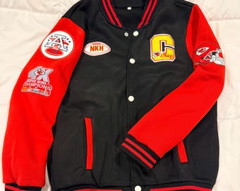 Puede incluir: Chaqueta universitaria negra y roja con cierre de botones blancos. La chaqueta presenta parches en las mangas y el pecho, incluyendo la letra "C" y la palabra "Chiefs". Las mangas son rojas y el cuerpo es negro con rayas rojas.