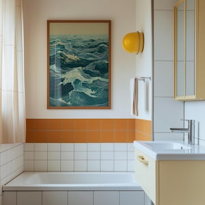 May include: A bathroom scene featuring a framed artwork depicting ocean waves in shades of blue and white. The room has a white bathtub, orange tile accents, and a yellow light fixture. A white towel hangs on a chrome towel rack.