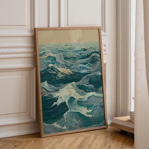 May include: A framed art print depicting a stylized ocean scene. The artwork features detailed waves in shades of teal, blue, and white, with a light beige sky. The print is in a natural wood frame, leaning against a white wall and wooden floor.