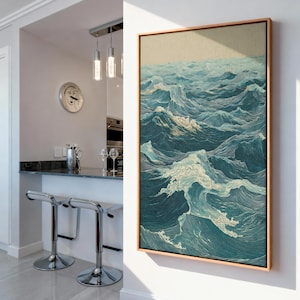 May include: A framed canvas print depicting a stylized ocean scene. The artwork features detailed waves in shades of teal and white, set against a neutral sky. The print is encased in a light brown wooden frame, adding a touch of warmth to the coastal theme.