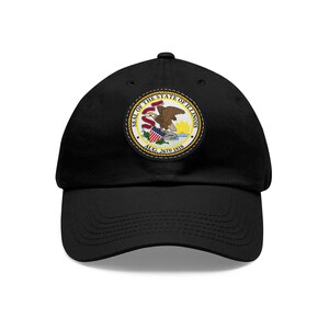Peut inclure: Casquette de baseball noire avec un patch brodé représentant le sceau de l'État de l'Illinois. Le sceau représente un aigle avec un bouclier et les mots "SEAL OF THE STATE OF ILLINOIS" et "AUG. 26TH 1818".