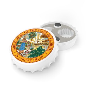 May include: White bottle opener featuring the Florida state seal. The seal is circular, with a woman, palm trees, and a ship. The text "GREAT SEAL OF THE STATE OF FLORIDA" and "IN GOD WE TRUST" are visible.