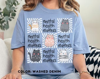 May include: A light blue t-shirt with a graphic of six cats and the text "mental health matters" repeated five times. The shirt is labeled "COLOR: WASHED DENIM".