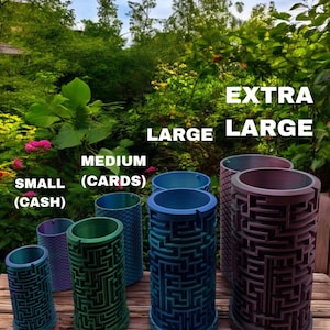 May include: A collection of six cylindrical containers with intricate maze patterns on the exterior, labeled by size as SMALL (CASH), MEDIUM (CARDS), LARGE, and EXTRA LARGE. The containers feature a gradient color finish and a textured base.