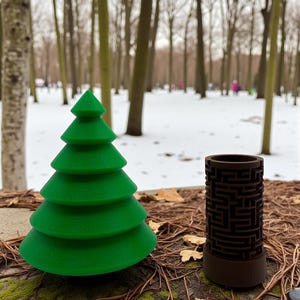 May include: A green, tiered Christmas tree and a brown cylindrical object with a maze design sit on a mossy surface. The background shows a snowy park with bare trees.
