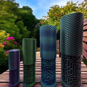 May include: Four cylindrical containers of varying heights, each featuring a textured diamond-patterned top section and a lower section with an intricate, raised maze design. The containers display a gradient of metallic colors including purple, green, and blue.