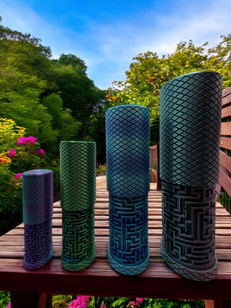 May include: Four cylindrical containers of varying heights, each featuring a textured diamond-patterned top section and a lower section with an intricate, raised maze design. The containers display a gradient of metallic colors including purple, green, and blue.