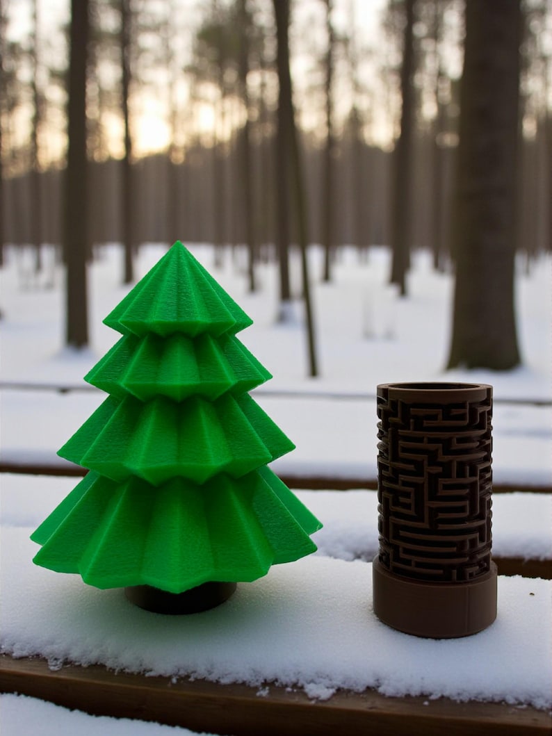 May include: A green, layered Christmas tree and a brown cylindrical maze game sit on a snow-covered surface. The tree has a dark base. The maze game is brown with a complex pattern. The background features a forest with snow and a soft, diffused light.
