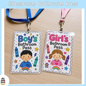 May include: Two rectangular classroom bathroom passes in clear plastic holders with lanyards. One pass features a blue lanyard and a cartoon boy with the text Boy's Bathroom Pass. The other has a pink lanyard and a cartoon girl with the text Girl's Bathroom Pass. Both include colorful crayon and star illustrations.