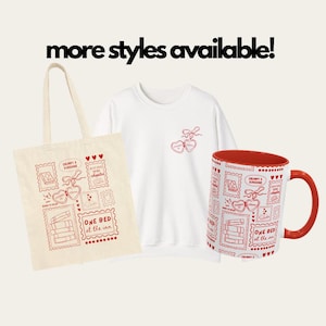 May include: A collection of merchandise featuring a red and white design. Includes a tote bag, a white sweatshirt, and a red-handled mug. The design features postage stamp-style illustrations with hearts, books, and the text "GRUMPY X SUNSHINE" and "ONE BED at the inn."