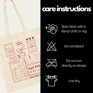 May include: Cream-colored tote bag with a red stamp-like design featuring book-related graphics and text. The text includes phrases like "Grumpy x Sunshine" and "One Bed at the Inn." Care instructions are on the right, including "Spot clean" and "Line dry."
