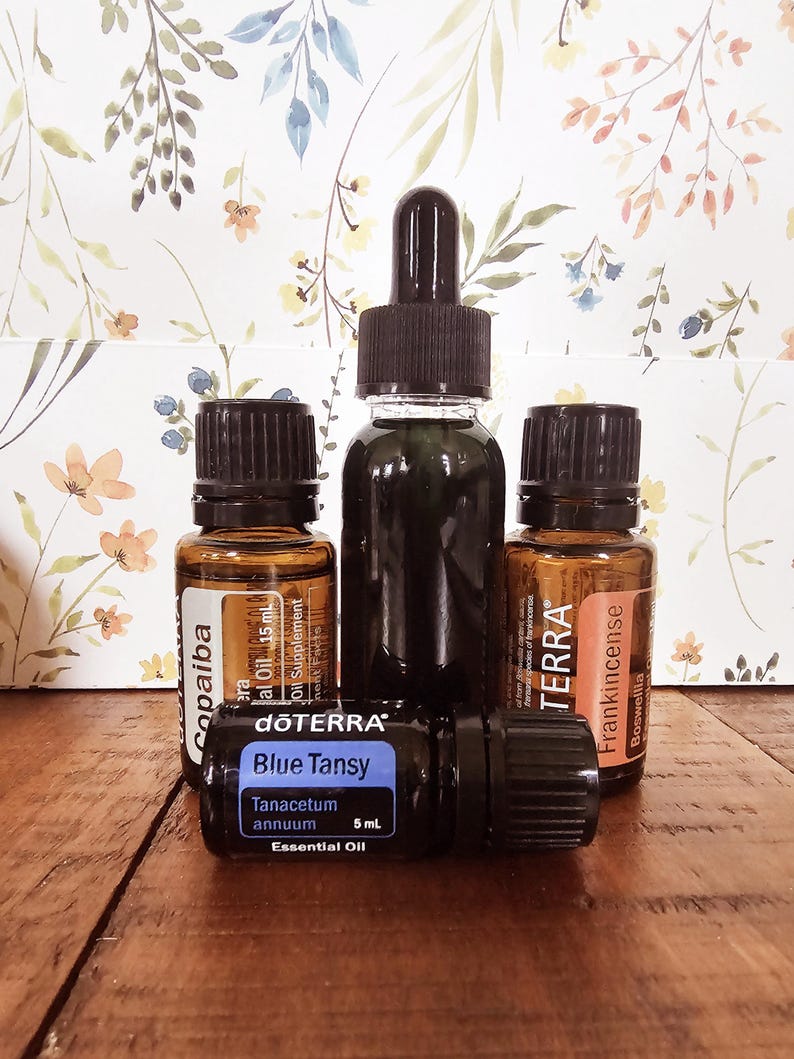 May include: Four small glass bottles of essential oils with black caps and droppers. The bottles are labeled "Copaiba", "Blue Tansy", "Frankincense", and "Terra".