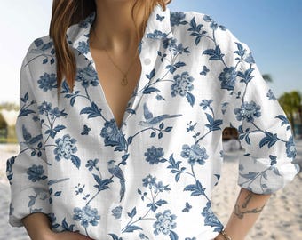 May include: White button-down shirt with a blue floral and bird pattern. The long-sleeved shirt features a classic collar and is made of a lightweight fabric. The design includes blue flowers, birds, and butterflies.