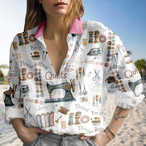 May include: White button-down shirt with a pink collar, featuring a sewing-themed pattern. The design includes sewing machines, spools of thread, scissors, buttons, and text like "Quilts" and "Cut once don't iron."